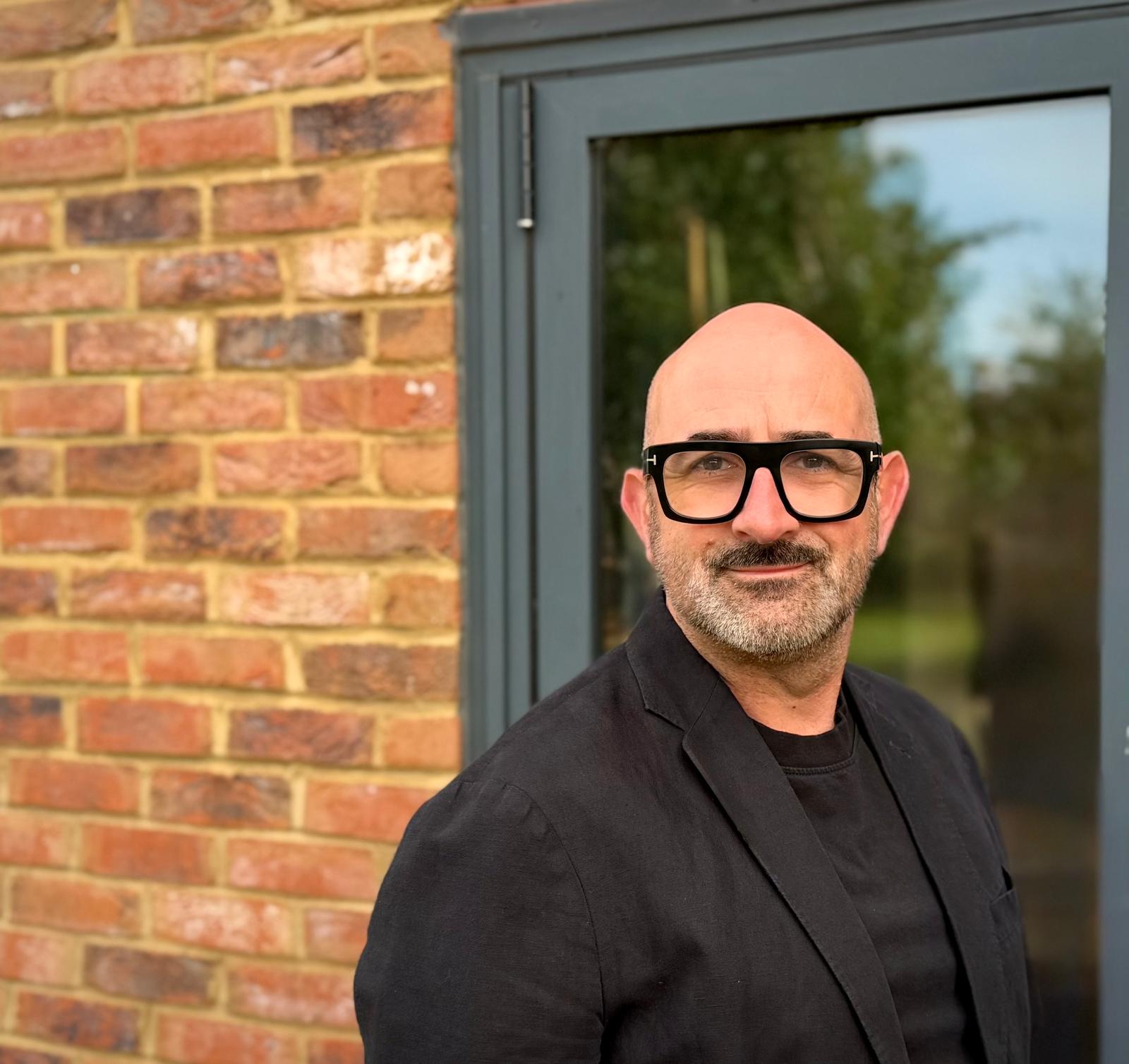 Richard Mason-Fowler standing in front of a brick wall and window