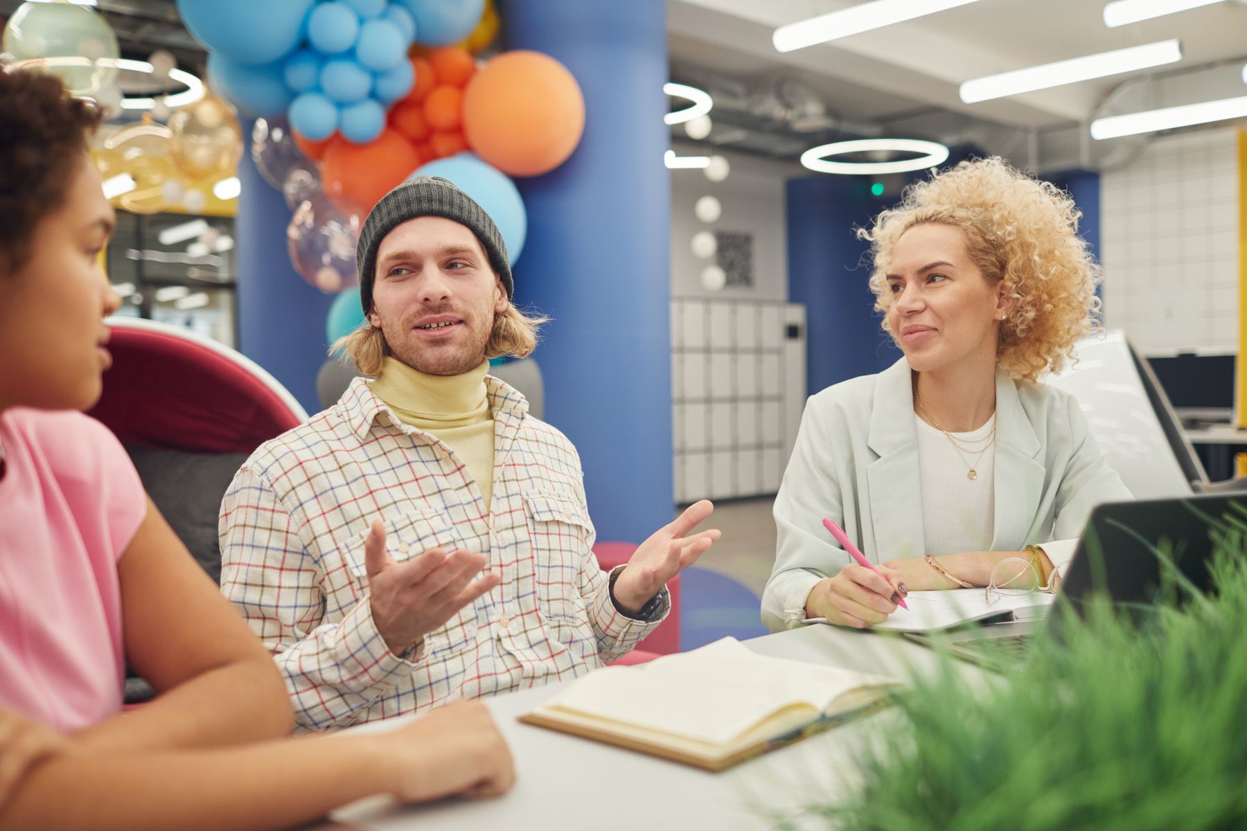 Three younger colleagues sharing ideas in a colourful workspace