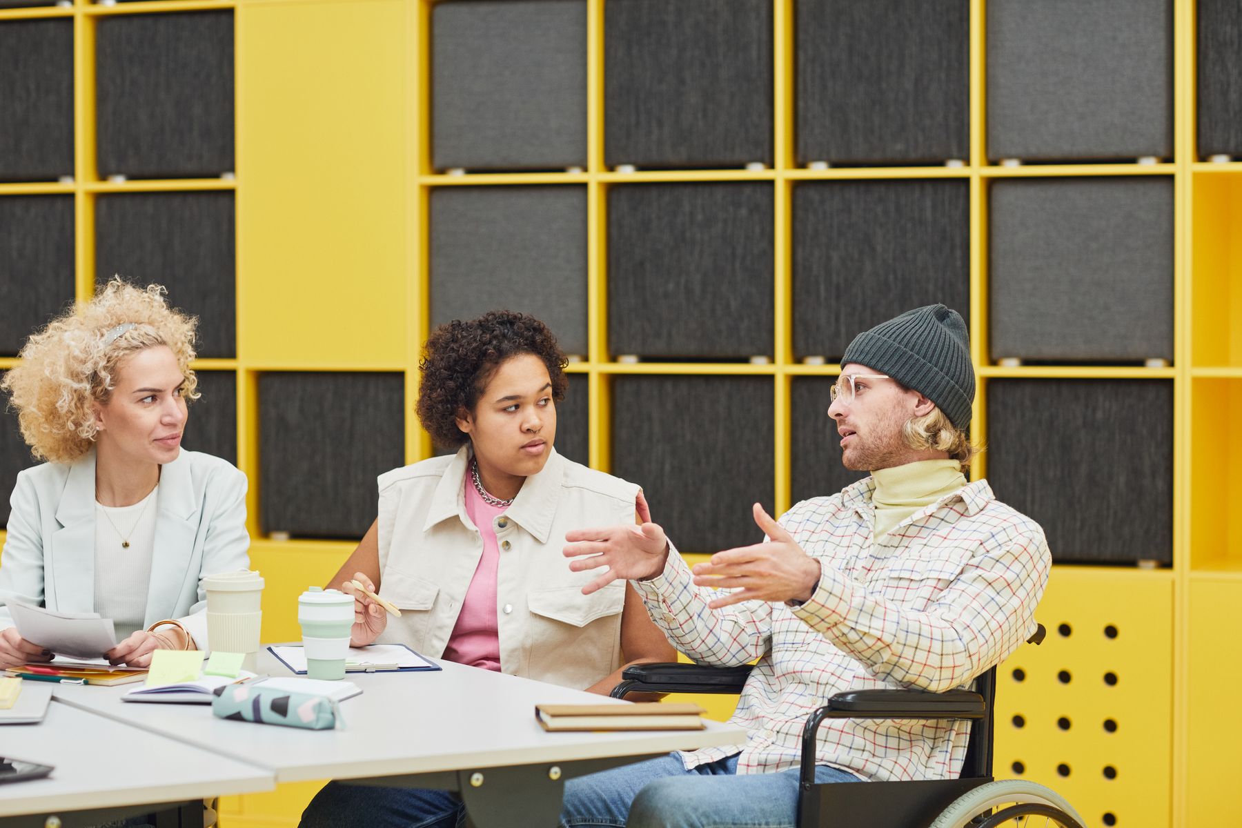 Three people taking part in an animated discussion against a bright yellow background